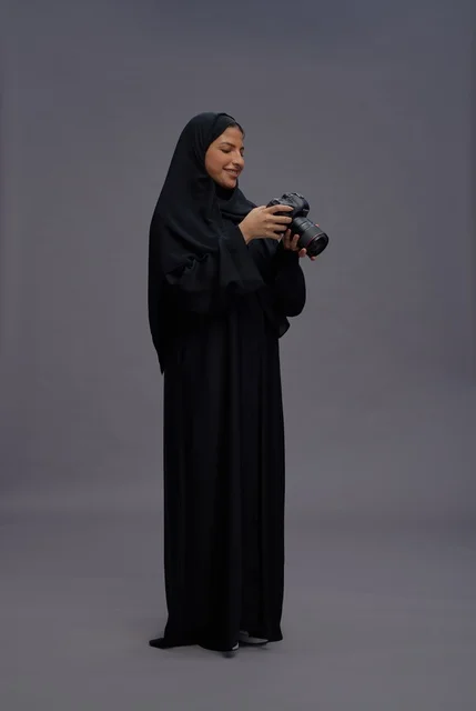 امرأة سعودية بالعباءة تمسك بكاميرا احترافية