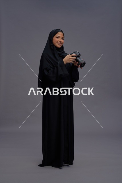 امرأة سعودية بعباية تحمل كاميرا احترافية