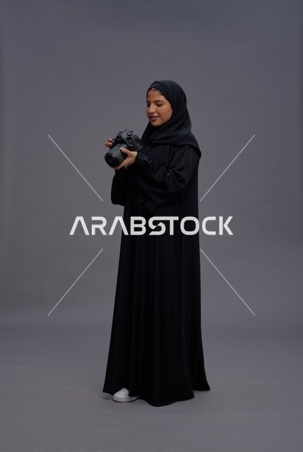 امرأة سعودية بالعباءة تمسك كاميرا احترافية