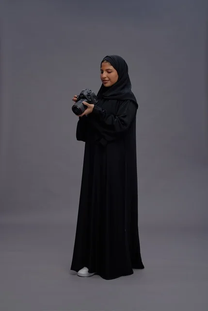 امرأة سعودية بالعباءة تمسك كاميرا احترافية