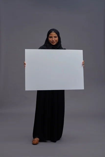 امرأة سعودية بعباية سوداء تحمل لوحة بيضاء فارغة