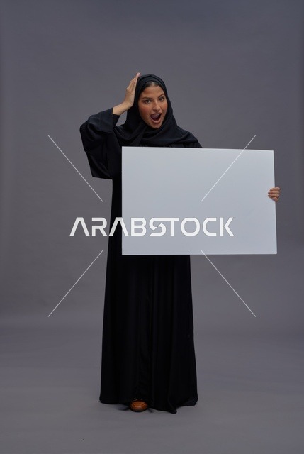 امرأة سعودية بعباية سوداء تحمل لوحة بيضاء فارغة