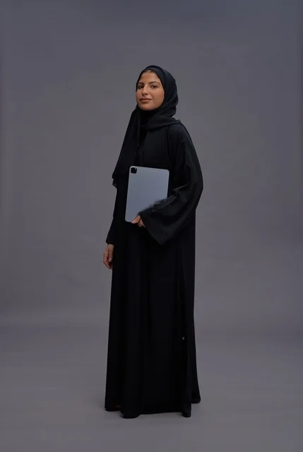 Saudi Woman in Abaya Holding Tablet on Gray Background