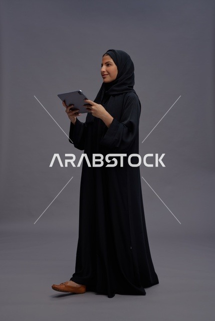امرأة سعودية بالعباءة السوداء تستخدم جهاز لوحي