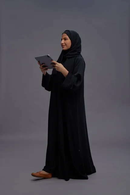 امرأة سعودية بالعباءة السوداء تستخدم جهاز لوحي
