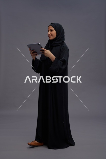 امرأة سعودية تستخدم جهازا لوحيا بخلفية استوديو