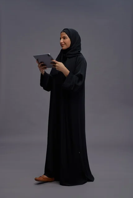 امرأة سعودية تستخدم جهازا لوحيا بخلفية استوديو