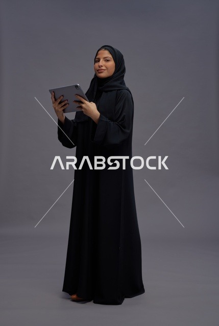امرأة سعودية بالعباءة السوداء تستخدم جهاز لوحي في الاستوديو