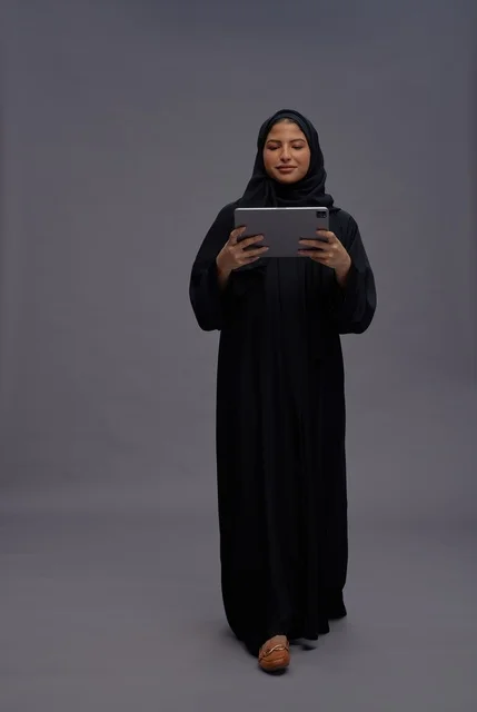 Saudi Woman Wearing Black Abaya Using Tablet in Studio