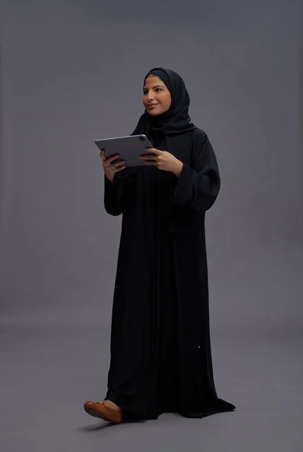 امرأة سعودية بالعباءة السوداء تستخدم جهاز لوحي في الاستوديو