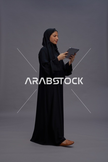 Saudi Woman Wearing Black Abaya Using Tablet in Studio