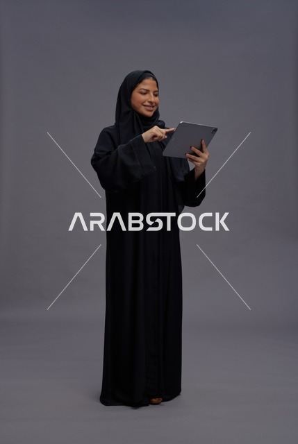 امرأة سعودية بالعباءة السوداء تستخدم جهاز لوحي