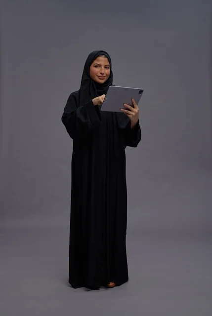 امرأة سعودية بالعباءة تستخدم جهاز لوحي في الاستوديو