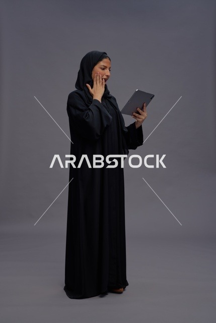 امرأة سعودية تستخدم جهاز لوحي بتعبير مندهش