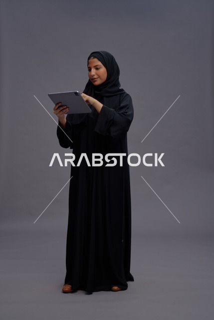 امرأة سعودية تستخدم جهازًا لوحيًا بالعباءة السوداء