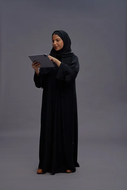 امرأة سعودية تستخدم جهازًا لوحيًا بالعباءة السوداء