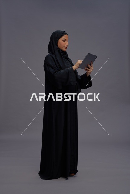 امرأة سعودية بالعباءة السوداء تستخدم جهاز لوحي