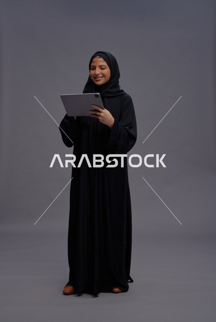 امرأة سعودية بعباءة سوداء تستخدم جهازاً لوحياً في الاستوديو