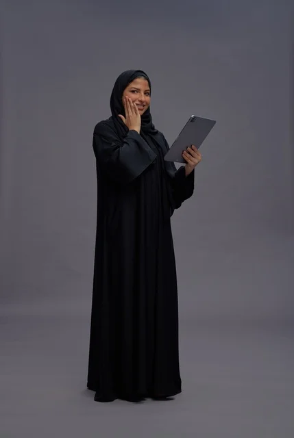 امرأة سعودية بالعباءة السوداء تستخدم جهاز لوحي