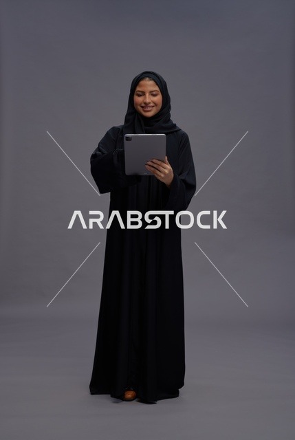 امرأة سعودية بالعباءة السوداء تستخدم جهاز لوحي