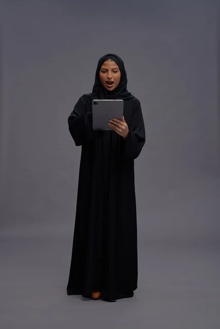 امرأة سعودية تستخدم جهازا لوحيا بتعبير وجه مندهش