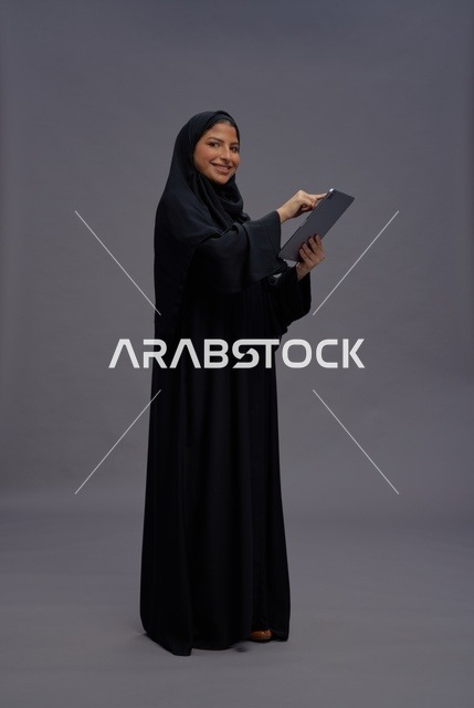 امرأة سعودية تستخدم جهاز لوحي بالعباءة السوداء