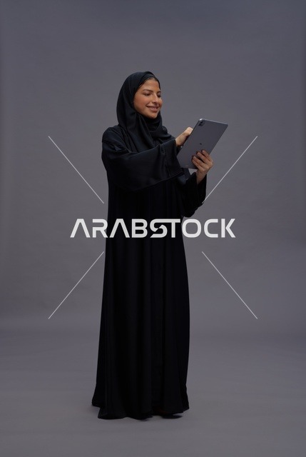 امرأة سعودية بالعباءة السوداء تستخدم جهاز لوحي