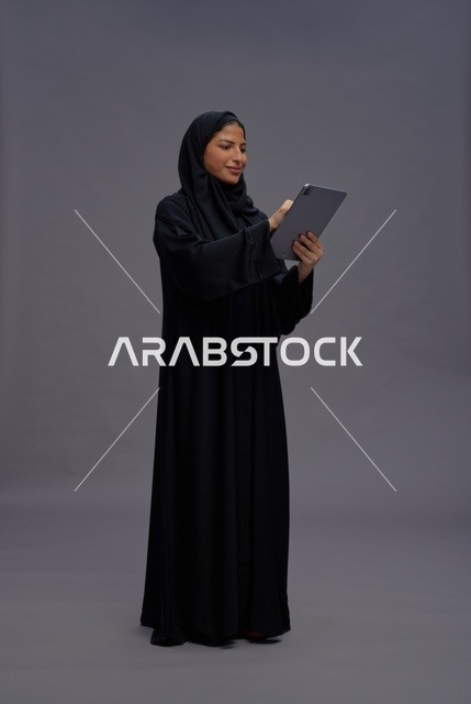 امرأة سعودية تستخدم جهازاً لوحياً بالعباءة في استوديو