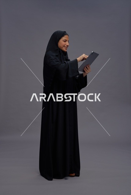 امرأة سعودية بالعباءة السوداء تستخدم جهاز لوحي