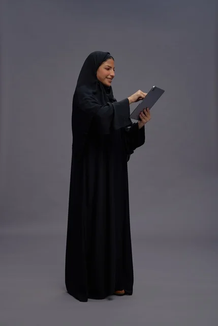 امرأة سعودية بالعباءة السوداء تستخدم جهاز لوحي