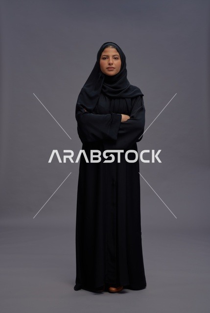 امرأة سعودية بالعباءة تقف بذراعين متقاطعتين