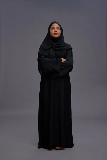 امرأة سعودية مرتدية عباءة سوداء تقف بذراعين متقاطعتين