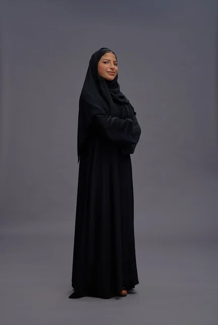 امرأة سعودية ترتدي عباءة سوداء وتقف بثقة