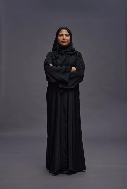 امرأة سعودية بالعباءة السوداء تقف بذراعين متقاطعتين