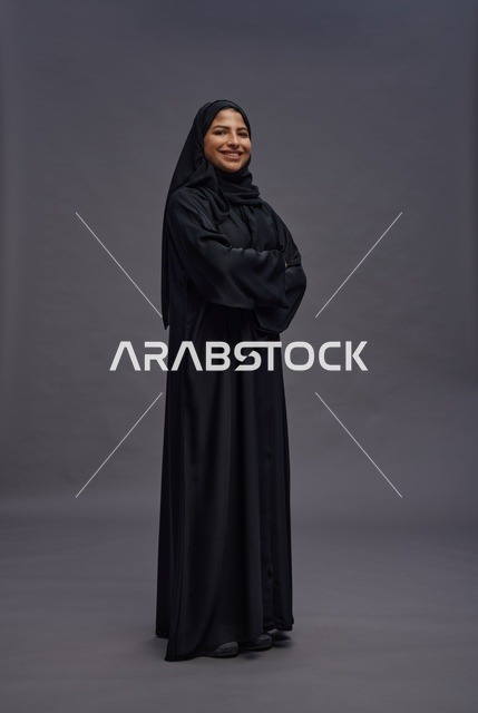 امرأة سعودية بعباءة سوداء تقف في استوديو