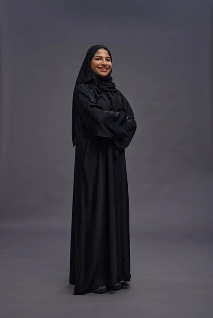 امرأة سعودية بعباءة سوداء تقف في استوديو