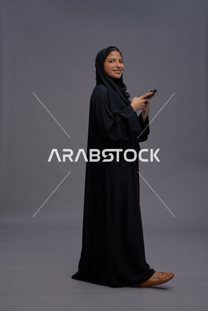 امرأة سعودية بالعباءة تستخدم الهاتف الذكي في الاستوديو