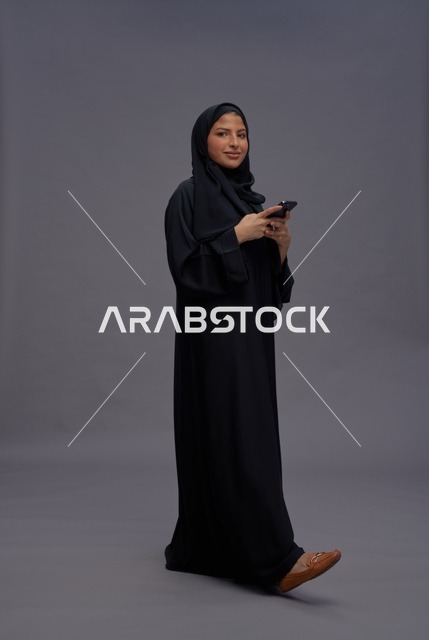 امرأة سعودية بالعباءة تستخدم الهاتف في الاستوديو