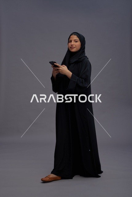 امرأة سعودية بالعباءة تستخدم الهاتف الذكي في الاستوديو
