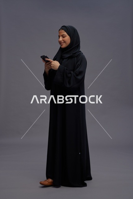 امرأة سعودية بالعباءة السوداء تستخدم الهاتف الذكي