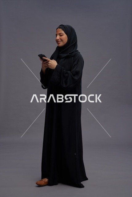 امرأة سعودية بالعباءة تستخدم الهاتف الذكي في الاستوديو