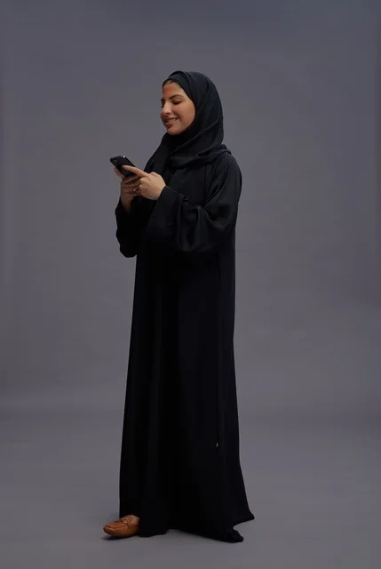 Saudi Woman in Abaya Using Smartphone in Studio