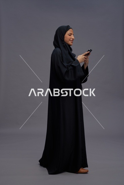 امرأة سعودية بالعباءة تستخدم الهاتف الذكي في الاستوديو