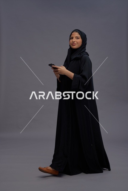 امرأة سعودية بالعباءة تستخدم الهاتف الذكي