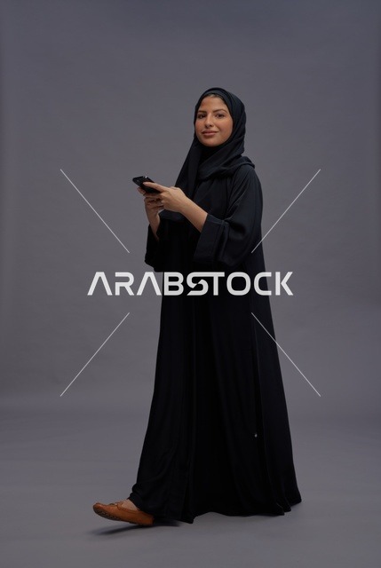 امرأة سعودية بالعباءة تستخدم الهاتف الذكي في الاستوديو