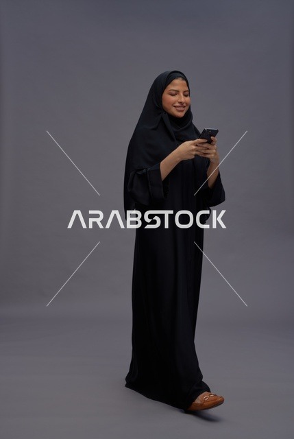 امرأة سعودية بعباءة سوداء تستخدم هاتف ذكي