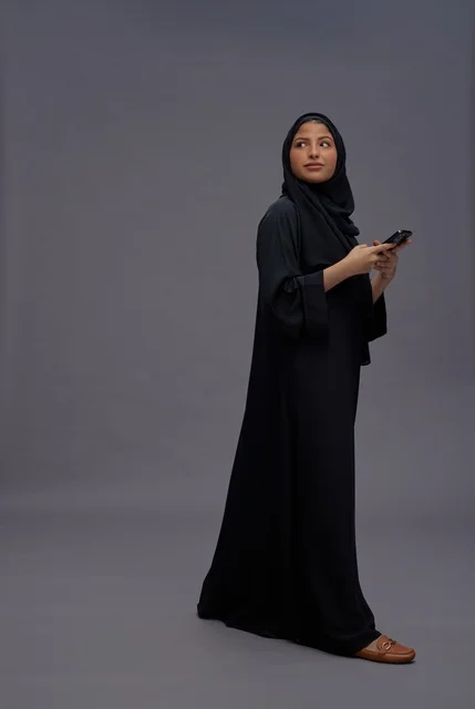 امرأة سعودية بالعباءة تستخدم هاتف ذكي في استوديو