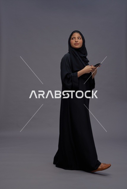 امرأة سعودية بالعباءة تستخدم الهاتف الذكي في الاستوديو