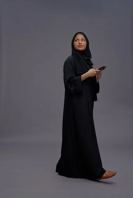 امرأة سعودية بالعباءة تستخدم الهاتف الذكي في الاستوديو