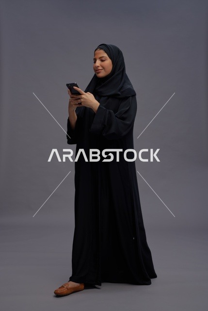 امرأة سعودية بالعباءة تستخدم الهاتف الذكي في الاستوديو